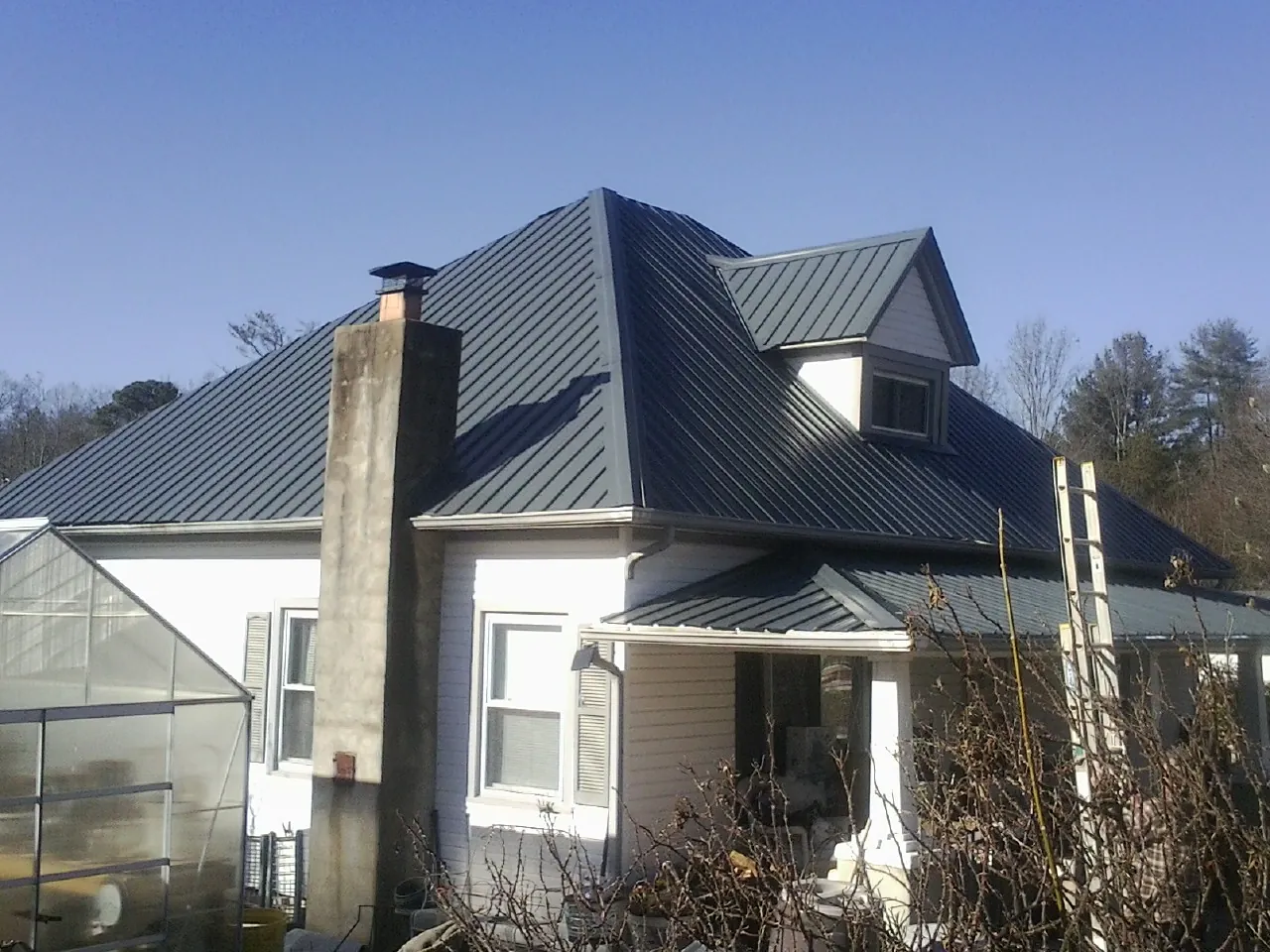 Dark blue standing seam metal roof on a white farmhouse with dormer — Slate & Tile Roof Repair by Roofing Brothers in Holland
